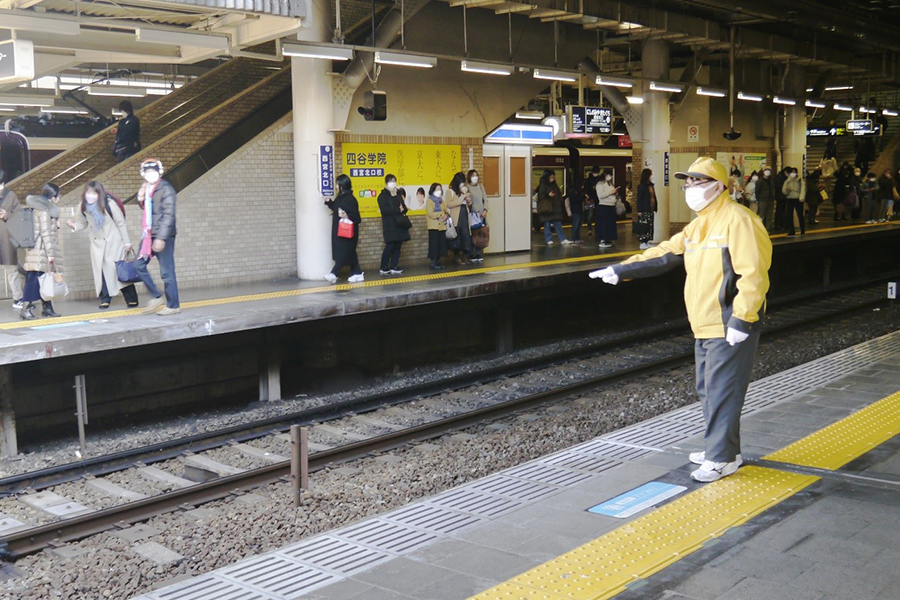 駅のホームで人が多い時に車両の扉をおさえてくれる黄色い服の人
