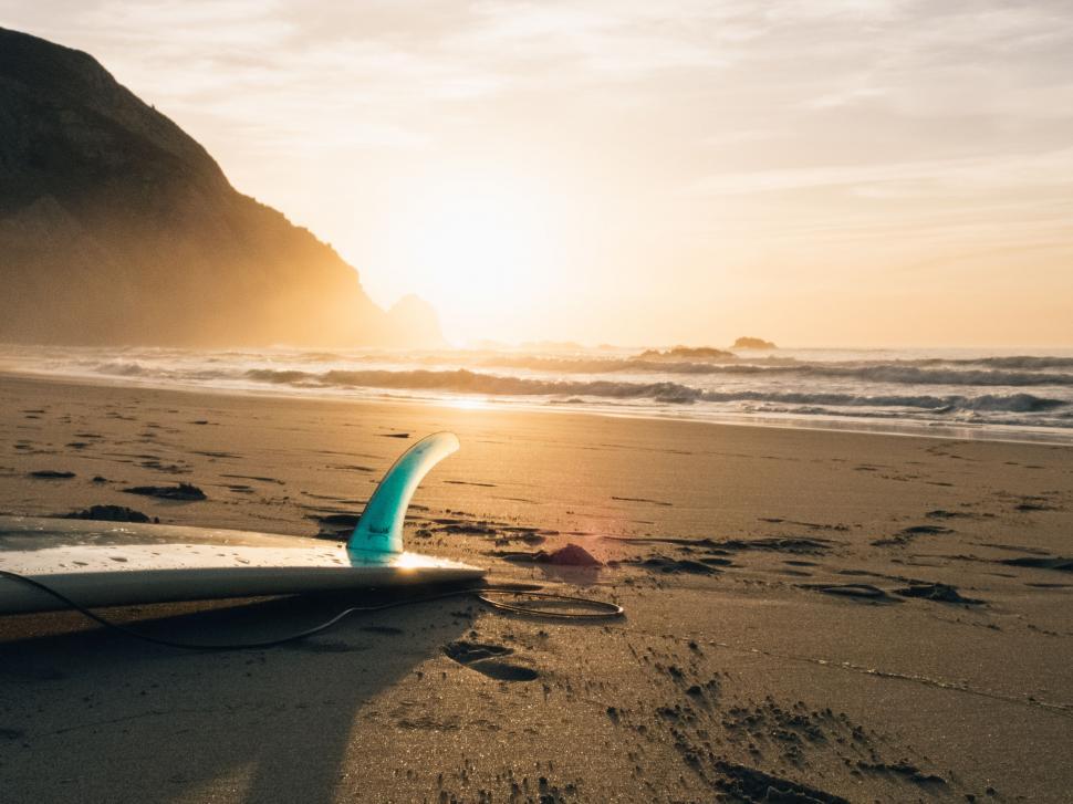 Free Stock Photo of Surfboard Resting on Beach at Sunset