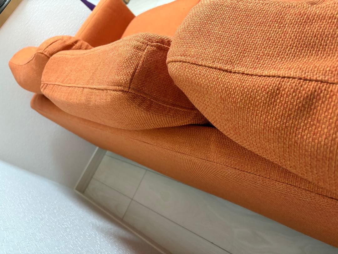 オレンジ色の3人掛けソファ